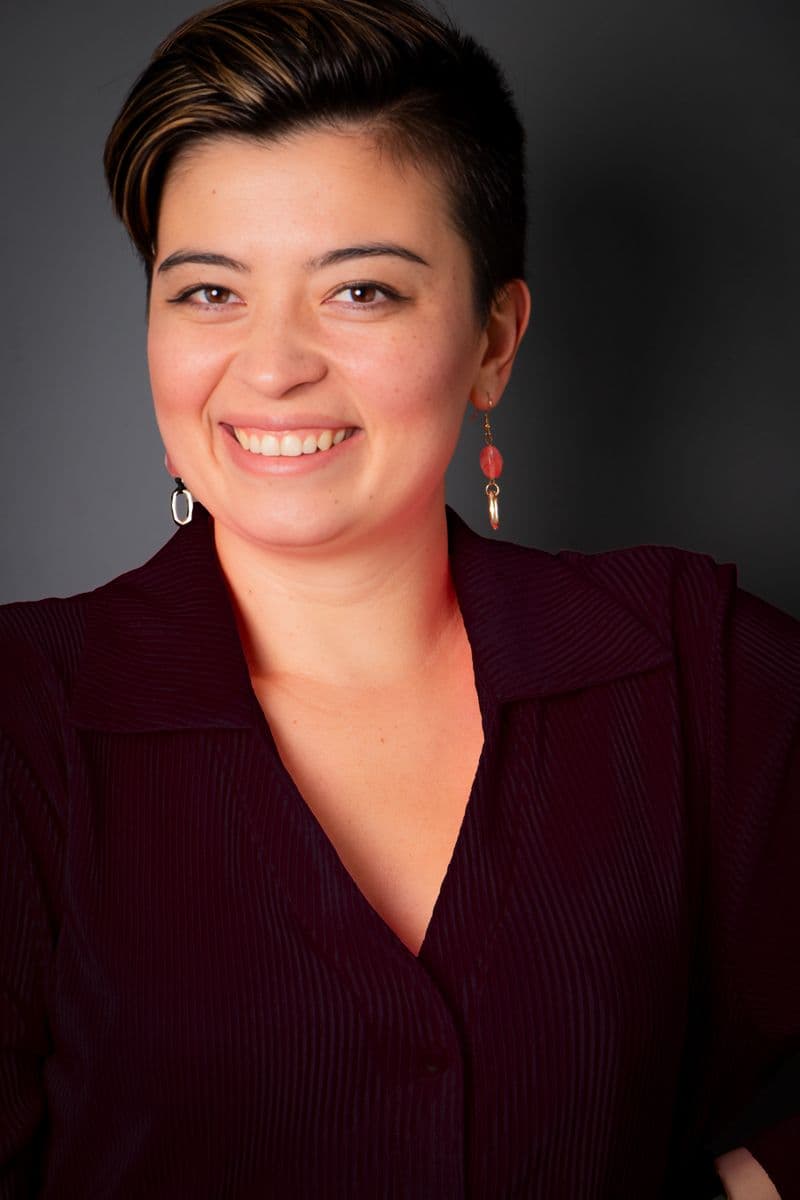 Portrait of a smiling woman with short hair against a dark studio background
