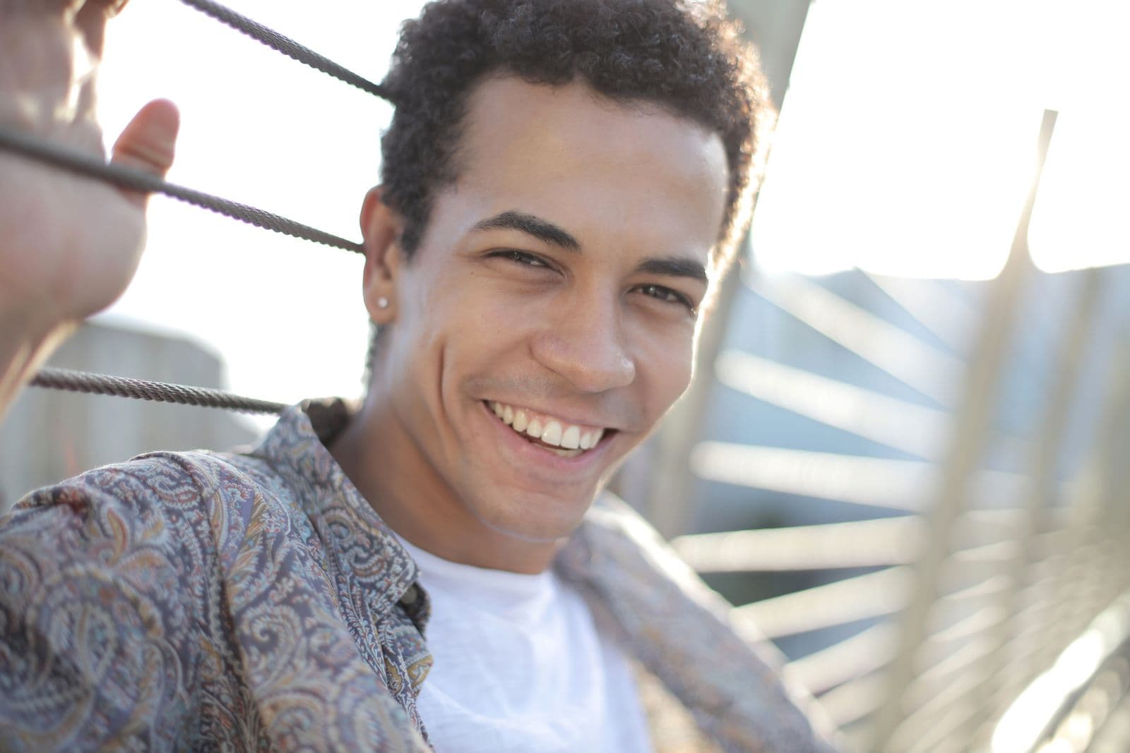 A young man with a big, bold, confident smile outdoors