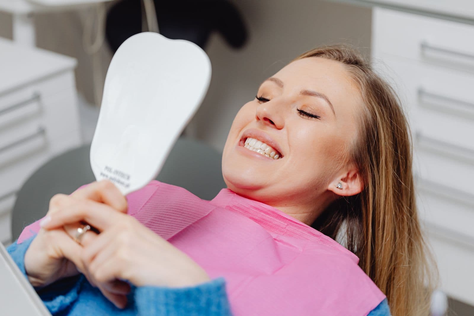 A hand holding a clear aligner tray against a plain background